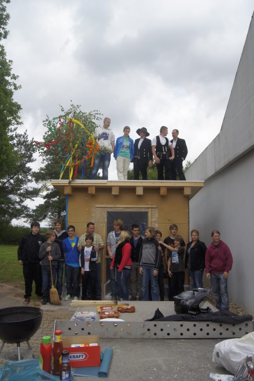 Eine Gruppe von Menschen versammelt sich auf einem Dach und auf dem Boden, umgeben von Aktivitäten.