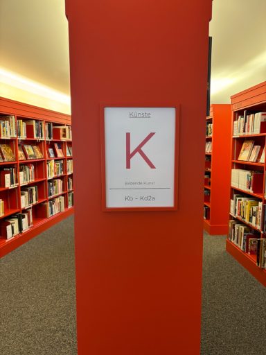 Rote Säule in einer Bibliothek mit einem Schild, das den Buchstaben "K" zeigt.