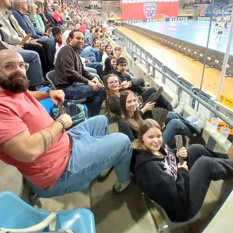 Schüler-meets-Azubi Gruppe von Personen in einem Raum, sitzend in Reihen, mit verschiedenen Ausdrücken.