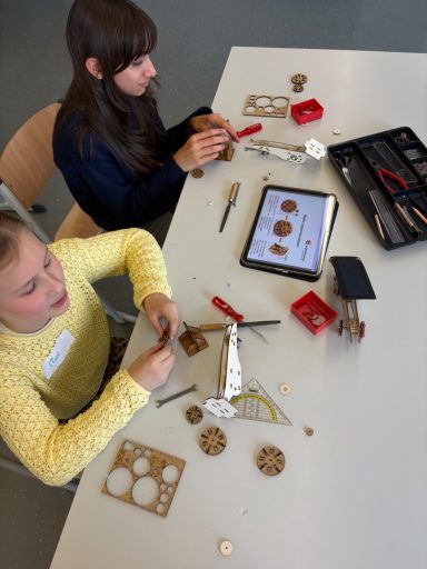 Zwei Mädchen arbeiten zusammen an einem Bastelprojekt mit Werkzeug und Materialien.
