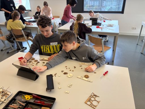 Zwei Jungen untersuchen gemeinsam Materialien auf einem Tisch in einem Klassenzimmer.