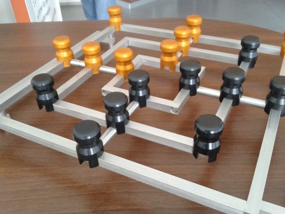 Schachspiel mit orangefarbenen und schwarzen Spielsteinen auf einem Holztablett.