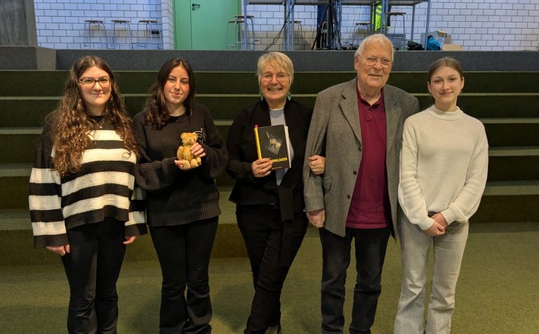 Schüler-meets-Azubi Gruppe von Personen in einem Raum, sitzend in Reihen, mit verschiedenen Ausdrücken.
