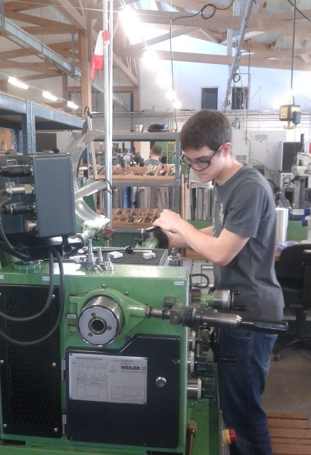 Junger Mann arbeitet an einer Maschinenanlage in einer Werkstatt.